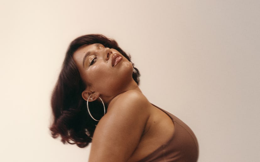 A woman poses confidently in a brown activewear outfit against a neutral background.